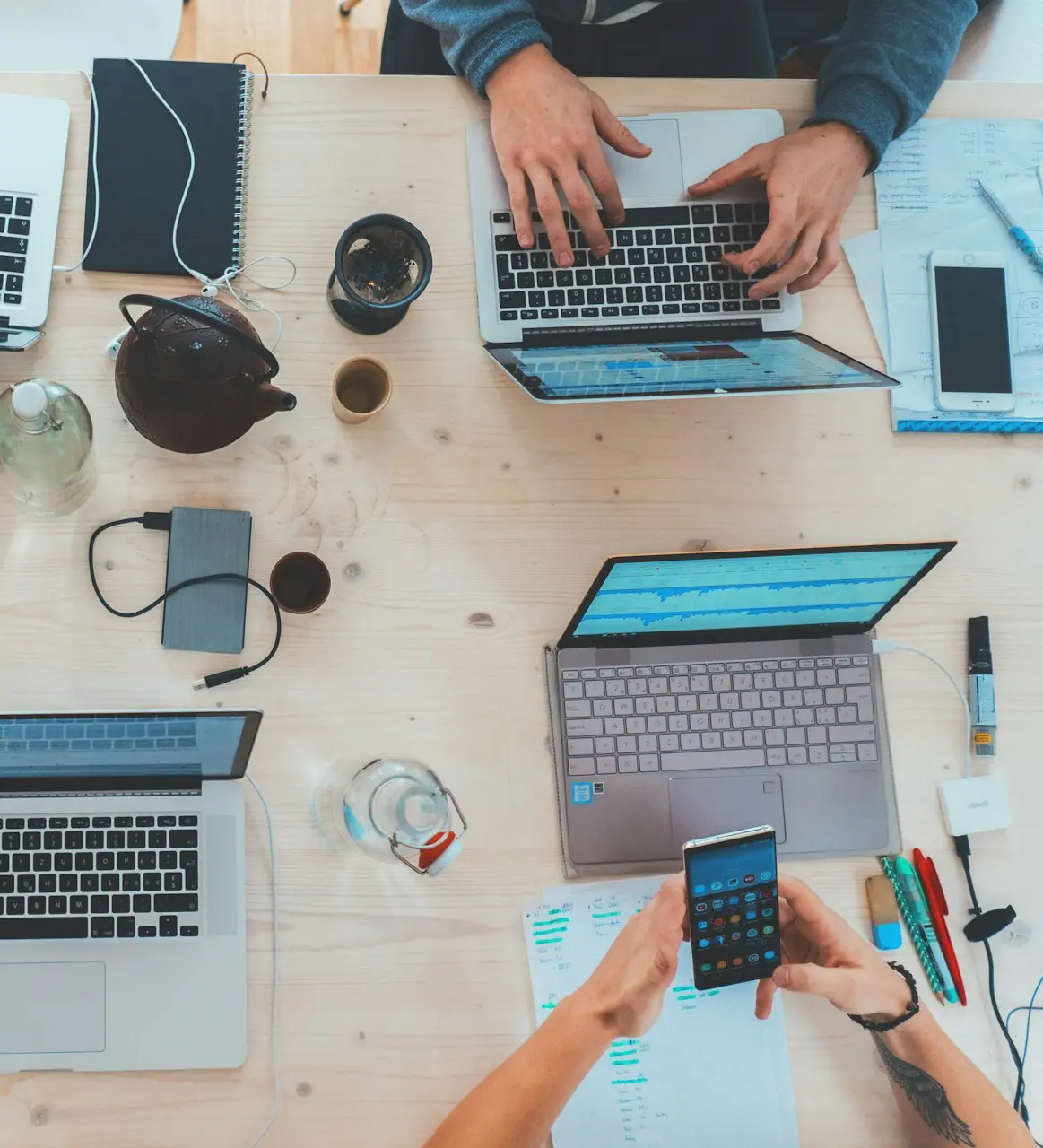 people sitting down near table with assorted laptop computers